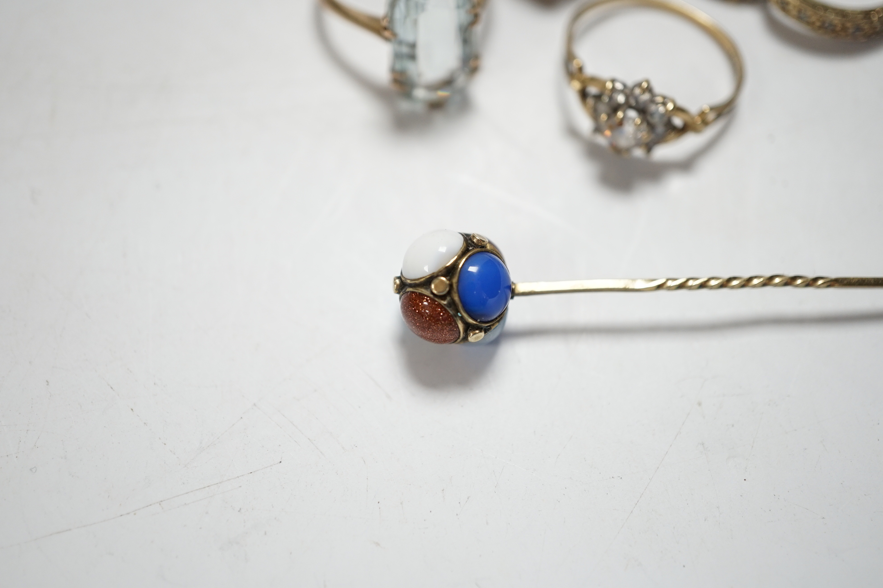 Four assorted modern 9ct and gem set rings including cubic zirconia, two other yellow metal and gem set rings including aquamarine and a yellow metal and multi gem set stick pin, gross weight 15.8 grams.